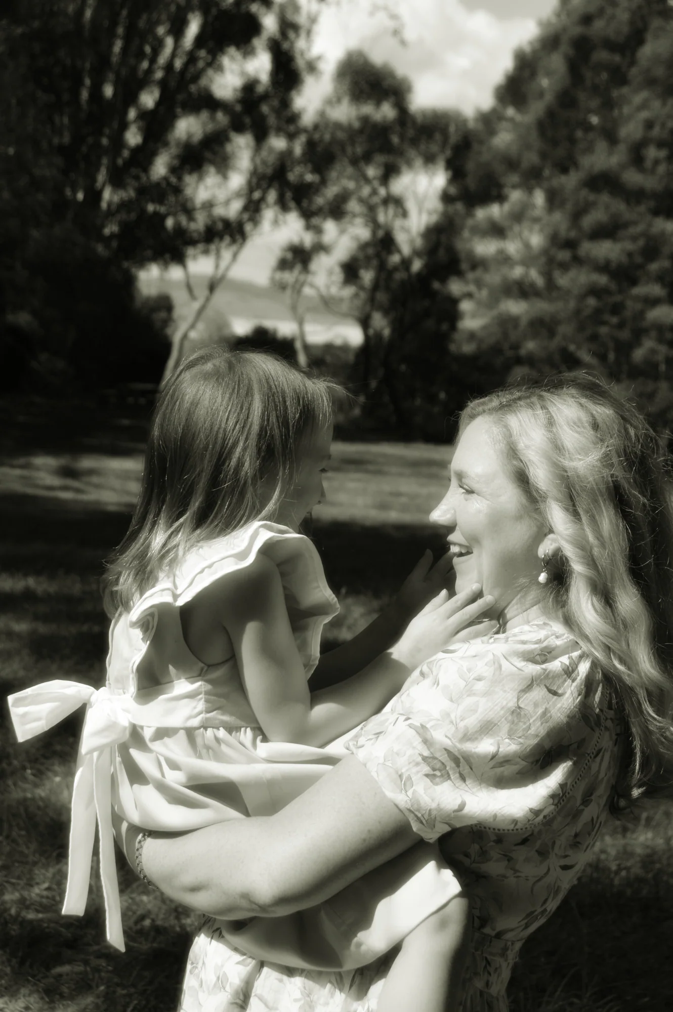 Mother holds young daughter face to face in black and white.